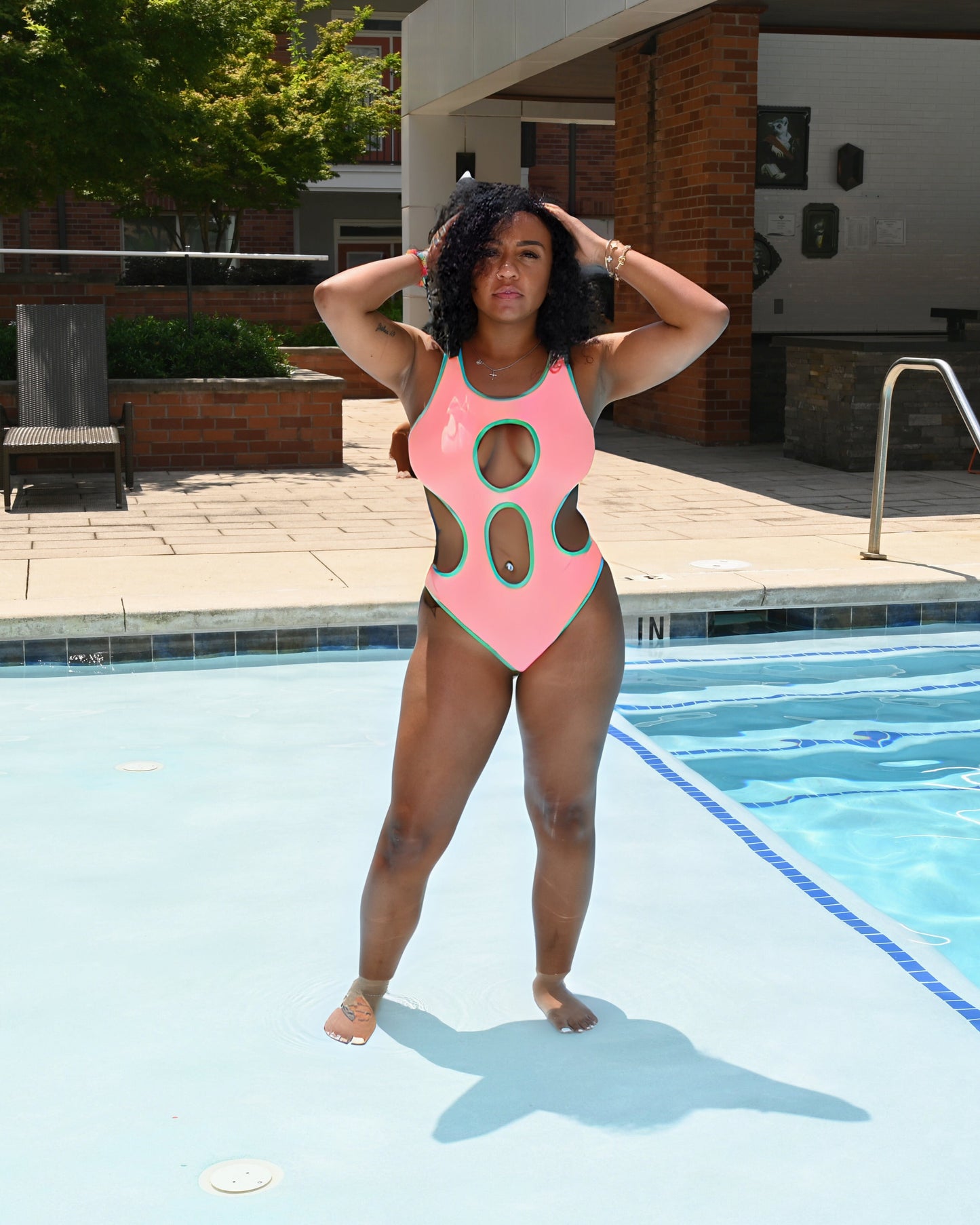 Woman in a pink swimsuit standing by a pool